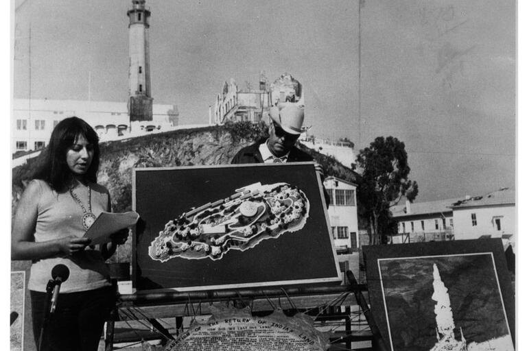 Image of LaNada War Jack speaking in front of a map of Alcatraz during the occupation
