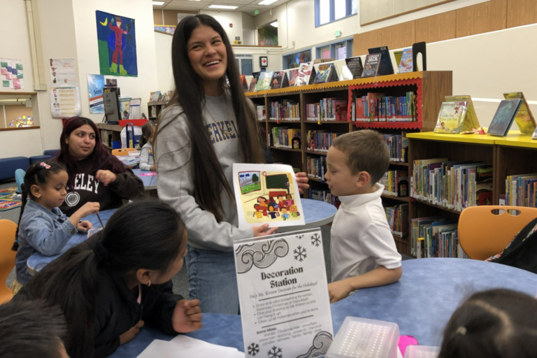 Image of student Dayane Silva reading her children's book to students at Hoover Elementary School in Oakland.